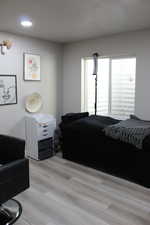 Bedroom with light hardwood / wood-style flooring and a textured ceiling