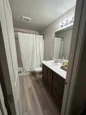 Full bathroom with wood-type flooring, toilet, vanity