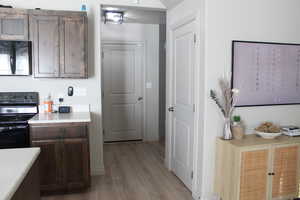 Kitchen featuring dark brown cabinetry, range, and light hardwood / wood-style flooring, door to bsmt and garage