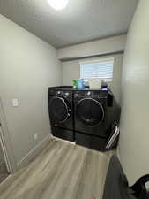 Washroom featuring washer and dryer, a textured ceiling, and light wood-type flooring