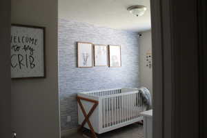 Bedroom featuring a nursery area and a textured ceiling