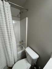 Bathroom featuring shower / tub combo with curtain and toilet