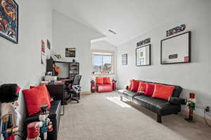 Home office with vaulted ceiling and carpet flooring