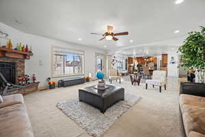 Carpeted living room featuring ceiling fan, a textured ceiling, a fireplace, and a healthy amount of sunlight