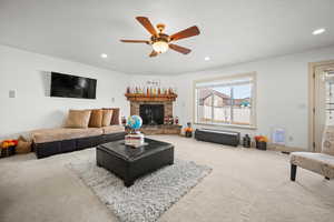 Living room featuring ceiling fan, a fireplace, and carpet floors