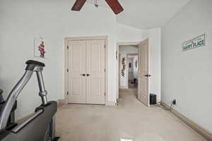 Exercise room with ceiling fan, lofted ceiling, and light carpet