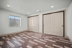 Unfurnished bedroom with multiple closets, a textured ceiling, and hardwood / wood-style flooring