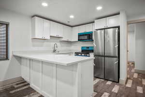 Kitchen with white cabinetry, appliances with stainless steel finishes, sink, and kitchen peninsula