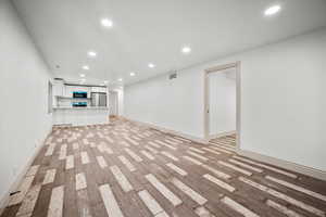 Basement with stainless steel refrigerator and light wood-type flooring