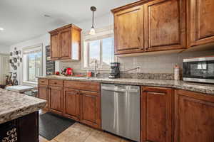 Kitchen featuring sink, tasteful backsplash, light tile patterned floors, stainless steel appliances, and light stone countertops