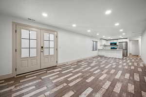 Unfurnished living room with french doors and light wood-type flooring