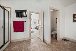 Bathroom featuring walk in shower, lofted ceiling, tile patterned floors, and toilet