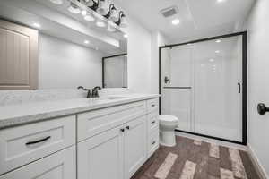 Bathroom with vanity, hardwood / wood-style floors, an enclosed shower, and toilet