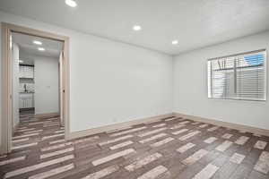 Unfurnished room featuring sink, dark hardwood / wood-style floors, and a textured ceiling