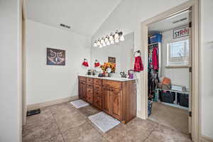 Bathroom featuring tile patterned floors, vanity, and vaulted ceiling