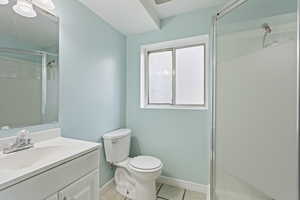 Bathroom with vanity, tile patterned flooring, a shower with door, and toilet