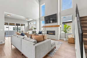 Living room with a fireplace, light hardwood / wood-style flooring, and a high ceiling