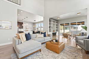 Living room with a high ceiling, sink, and light wood-type flooring