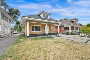 Bungalow featuring covered porch and a front yard