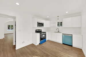 Kitchen featuring sink, white cabinetry, tasteful backsplash, pendant lighting, and stainless steel appliances