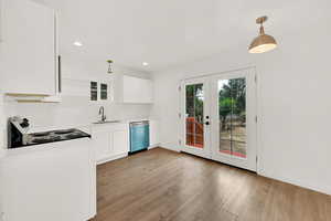 Kitchen with hanging light fixtures, white cabinetry, sink, and stainless steel dishwasher