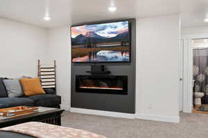 Basement Living room featuring light carpet and Built-In Electric Fireplace