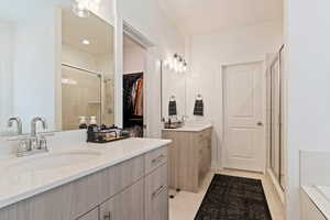 Bathroom featuring 2 vanities, a shower with shower door, and tile patterned flooring.  Barn Door Opening.