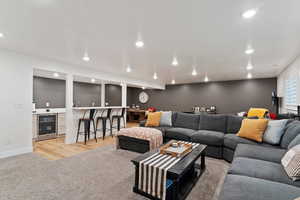 Basement Living room featuring bar, wine cooler, and light colored carpet