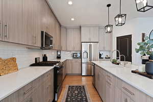 Kitchen featuring sink, light hardwood / wood-style flooring, appliances with stainless steel finishes, hanging light fixtures, and light brown cabinetry