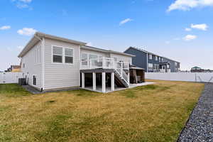 Back of property with central AC unit, a lawn, a patio, and a deck