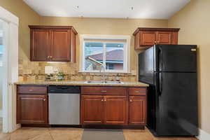 Kitchen with dishwasher, black fridge, sink, and decorative backsplash