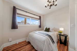 Bedroom with dark hardwood / wood-style flooring and a notable chandelier