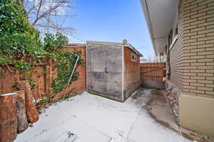 Snow covered patio with a storage shed