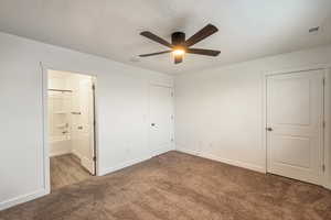 Unfurnished bedroom with ceiling fan, ensuite bathroom, and light carpet