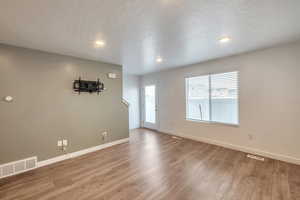 Empty room with wood-type flooring and a textured ceiling