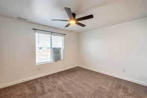 Carpeted spare room with a textured ceiling and ceiling fan