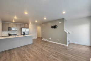 Kitchen featuring sink, light hardwood / wood-style flooring, gray cabinets, stainless steel appliances, and a textured ceiling