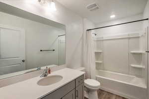 Full bathroom with hardwood / wood-style flooring, vanity, toilet, and shower / tub combo