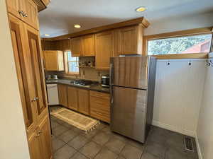 Kitchen with backsplash, stainless steel appliances, and dark tile patterned floors