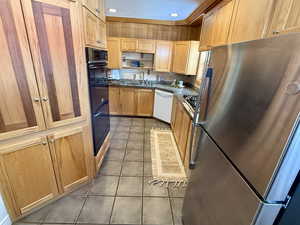 Kitchen with double oven, sink, stainless steel fridge, white dishwasher, and tile patterned floors