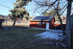 Exterior space featuring an outdoor structure, a lawn, and a patio area