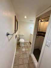 Bathroom featuring a tile shower, vanity, and toilet