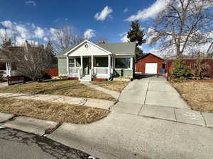 View of front of house featuring a garage, an outbuilding, covered porch, and a front lawn