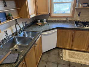 Kitchen with stainless steel gas stovetop, dishwasher, sink, and decorative backsplash