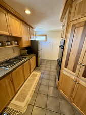 Kitchen featuring tasteful backsplash, tile patterned floors, and stainless steel appliances