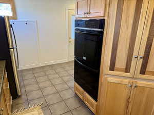 Kitchen featuring light tile patterned floors, stainless steel fridge, and double oven