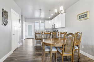 Dining space with an inviting chandelier and dark LVP / wood-style flooring