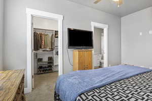 Bedroom featuring ceiling fan, ensuite bathroom, light carpet, a spacious closet, and a closet