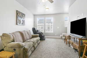 Carpeted living room featuring ceiling fan