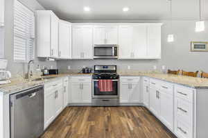 Kitchen featuring stainless steel appliances, sink, pendant lighting, and white cabinets